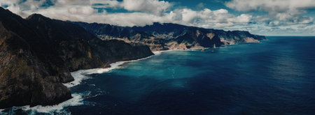 A breathtaking aerial view of a rugged coastline with crystal-clear waters, majestic mountains, and...