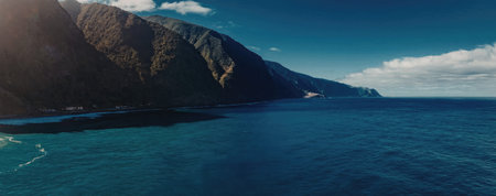 A tranquil ocean scene featuring a vast expanse of blue water, a mountainous coastline, and a clear...