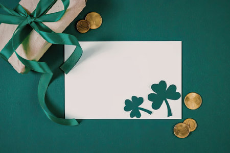 A gift wrapped in brown paper and tied with a green ribbon, a white card with two green shamrocks,...