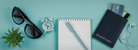 A neatly arranged collection of travel items including sunglasses, an alarm clock, a notepad with a...