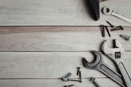 A selection of tools and hardware laid out on a wooden workbench, including a wrench, screwdrivers,...
