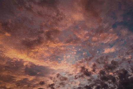 The image captures a breathtaking scene of vibrant sunset clouds against a blue sky, with shades of...