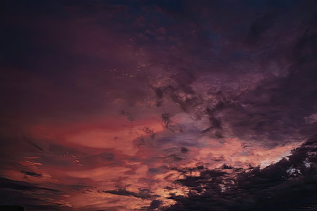 A breathtaking sunset scene with a predominantly dark cloud-filled sky illuminated by vibrant hues...