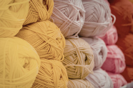A close-up image of neatly stacked balls of yarn in a variety of bright and pastel colors,...