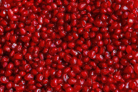 This image presents a close-up view of numerous fresh pomegranate seeds, showcasing their vibrant...