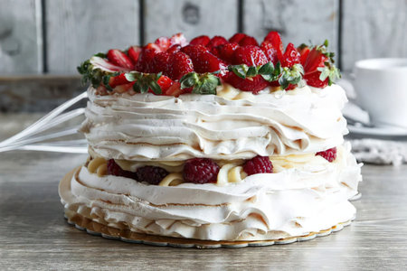 A layered meringue cake topped with strawberries and whipped cream