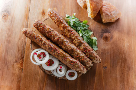 A plate of kebabs with onions and herbs on a wooden table