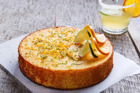 A moist and flavorful orange cake with a golden crust, topped with fresh orange slices and zest,...