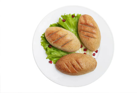 Three grilled chicken breasts on a white plate with lettuce and pomegranate seeds
