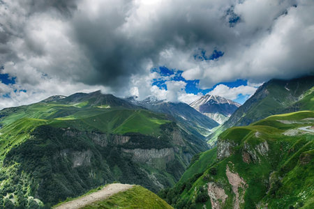 A scenic view of a mountain range with lush greenery and a cloudy sky.