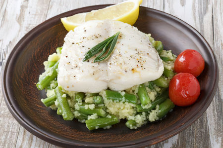 A plate of food with fish on top of asparagus, accompanied by cherry tomatoes and lemon