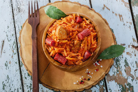A bowl of sausage and rice on a wooden plate with a fork
