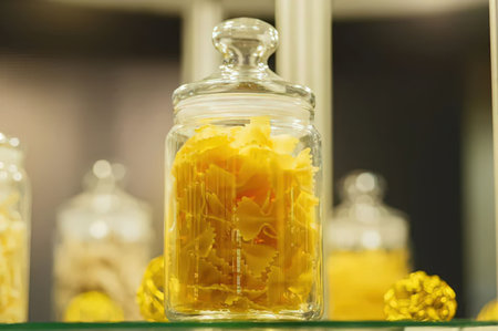 A glass jar filled with a yellow substance, possibly a chemical or food item, with other jars in the...