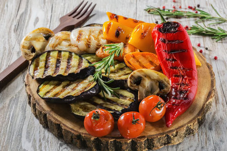 A vibrant platter of grilled vegetables, including red bell pepper, mushrooms, eggplant, zucchini,...