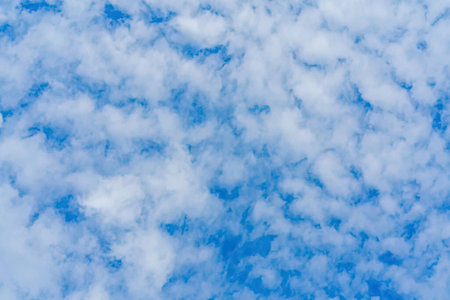 The image depicts a blue sky filled with white clouds.