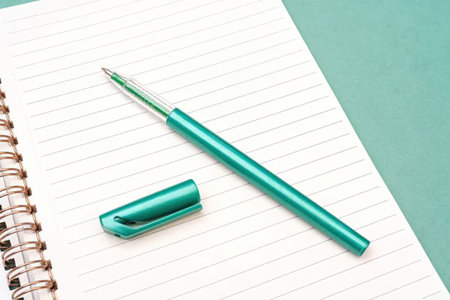 A green pen and its cap on a lined notebook page