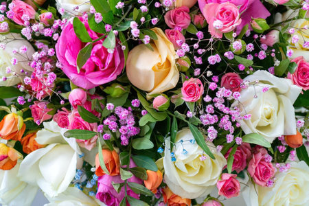 A vibrant and colorful bouquet of roses and other flowers in shades of pink, white, and orange.の写真素材