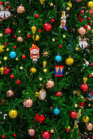 A close-up of a Christmas tree decorated with various colorful ornaments, balls, and lights.