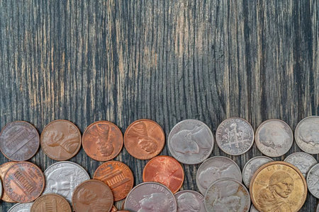 A collection of various coins arranged on a dark wooden surface