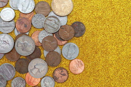 A pile of various coins on a yellow surfaceの写真素材
