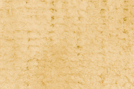 This image shows a close-up view of a beige textured surface. The surface appears to have a rough,...