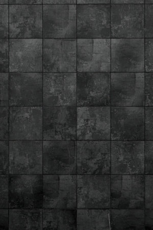 A close-up view of a dark grey tiled wall with a textured, square tile pattern.の写真素材