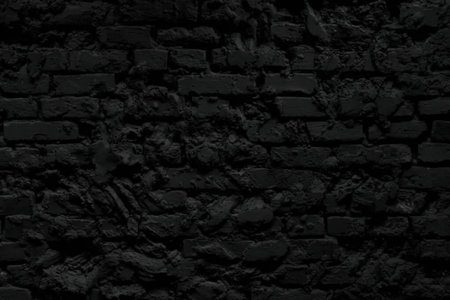 A dark brick wall with a rough texture, providing a somber and mysterious background.の写真素材