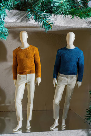 Two mannequins standing side by side wearing different colored sweaters and white pantsの写真素材