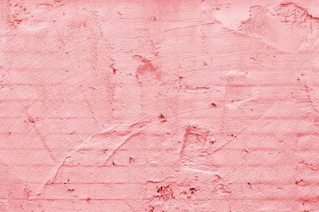A close-up view of a pink painted wall with a rough texture, showing brush strokes and imperfections.の写真素材