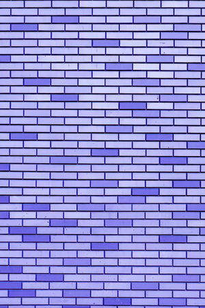 A close-up of a purple brick wall with varying shades of purple bricks