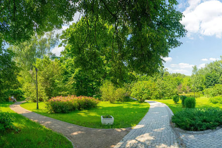 A winding pathway through a well-manicured park with lush greenery and trees.