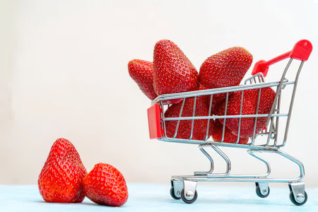 A shopping cart filled with strawberries and a few strawberries on the floorの写真素材