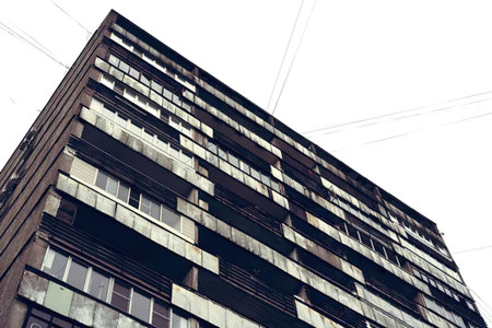 Sleek modern apartment building stands tall with numerous balconies and windows against a bright...