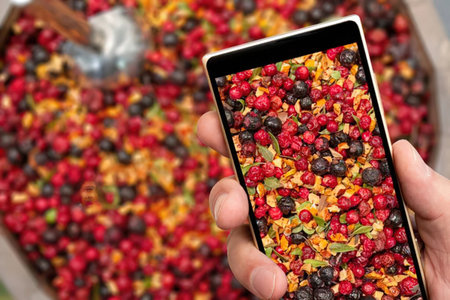 Person holding smartphone with closeup photo of vibrant mixture of red, orange, and black dried...