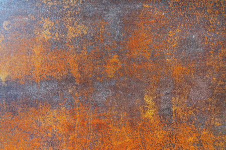 Rusty metal surface exhibits orange and gray tones creating a weathered textured background suitable...