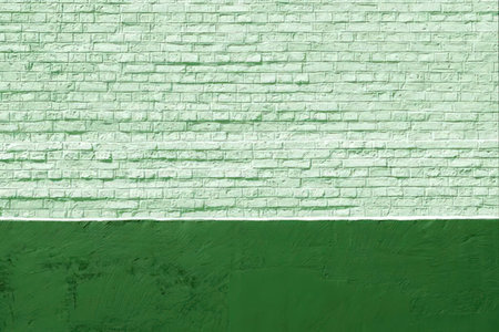 Light green brick wall texture above a dark green painted surface creating a contrasting visual effect with visible texture and pattern.の写真素材