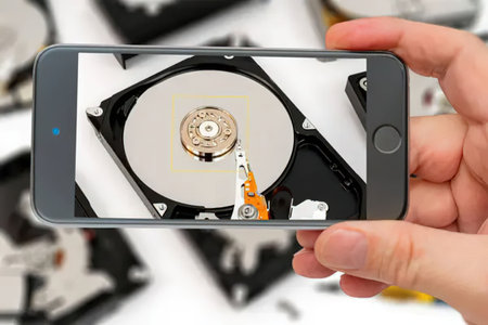 Person holds smartphone displaying a hard drive image with a highlighted section showing internal...