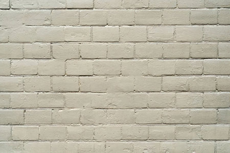 Off white painted brick wall showcasing a textured surface in a uniform pattern, typically used as...