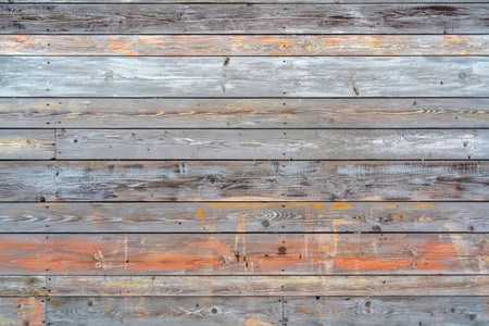 Weathered wooden plank wall showing various shades of brown and gray with subtle orange hues and...