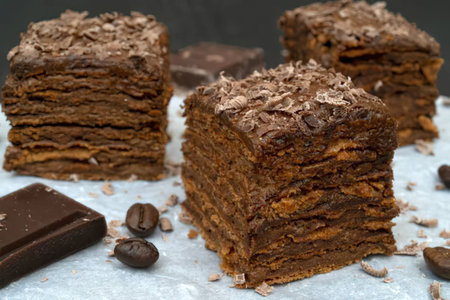 Chocolate layered cake with shaved chocolate on top surrounded by coffee beans and chocolate pieces...