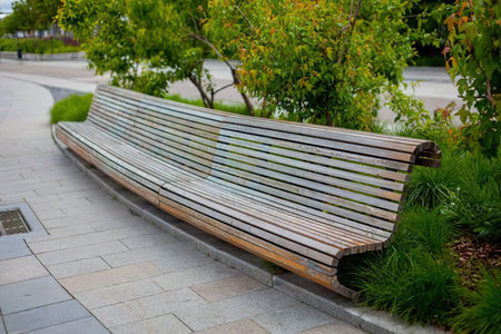 Modern outdoor wooden bench surrounded by lush greenery in a serene urban park setting quietly...