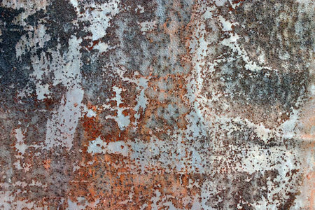Rusty metal surface shows flaking paint and corrosion damage in various colors and textures,...