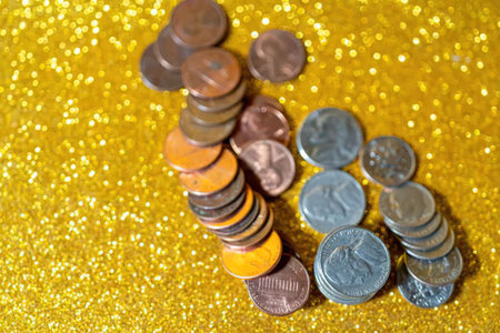 Stacks of coins arranged on a bright yellow glitter background symbolizing financial growth and...