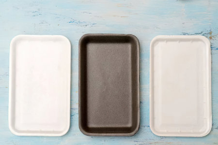 Three rectangular baking trays in white and black colors are arranged side by side on a distressed...