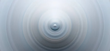 A single water droplet creates a ripple effect on a calm surface, forming concentric circles that...