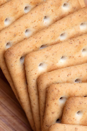 Stack of saltine crackers neatly arranged on a wooden surface, perfect for snacking and enjoying...
