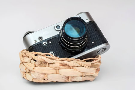 Vintage camera rests on a woven wicker basket, showcasing classic photography equipment and retro...