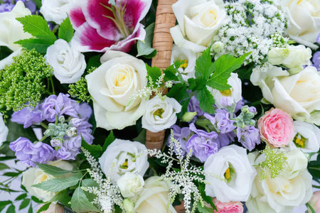 Beautiful bouquet of white roses, purple flowers, and pink roses arranged in a wicker basket with...