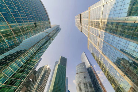 Modern glass skyscrapers stand tall in a city financial district reflecting the clear blue sky from...