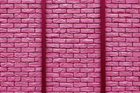 Pink painted brick wall with two downspouts attached to exterior wall surface showing detailed...